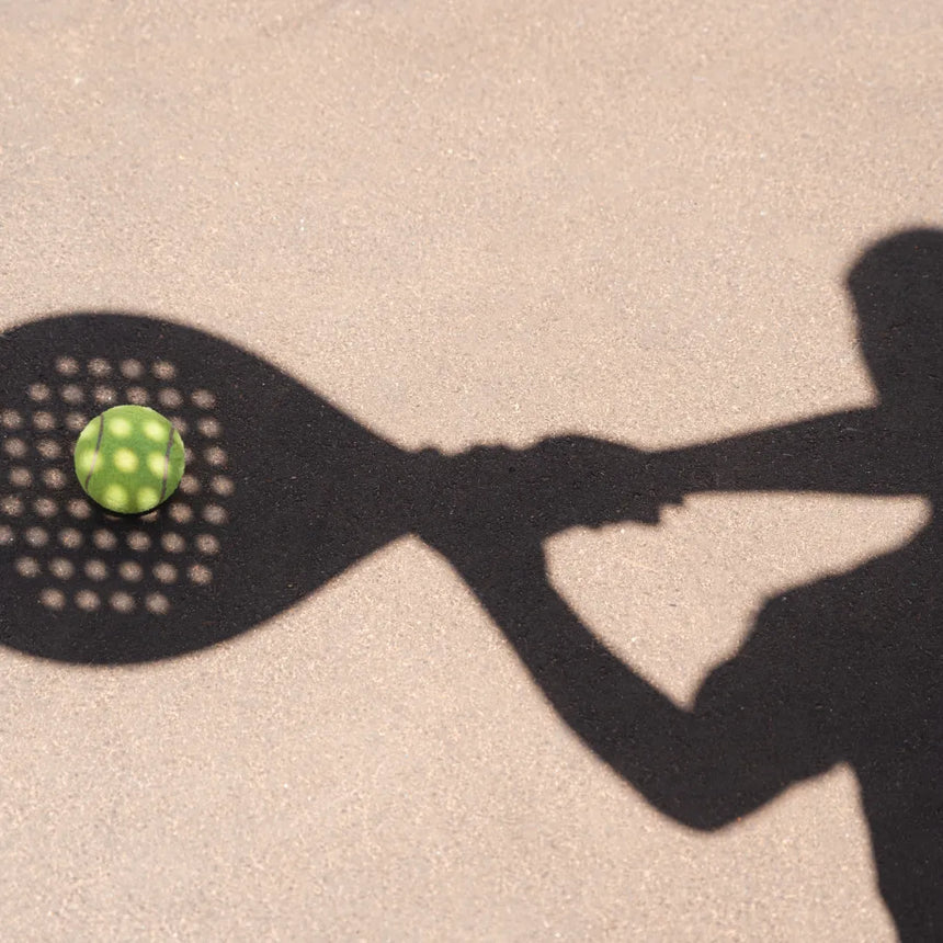 Shadow of a person holding a paddle, ready to hit a padel ball on a sunlit court, during the 60-Min Private Lesson w/ Dani by Padel Smash.