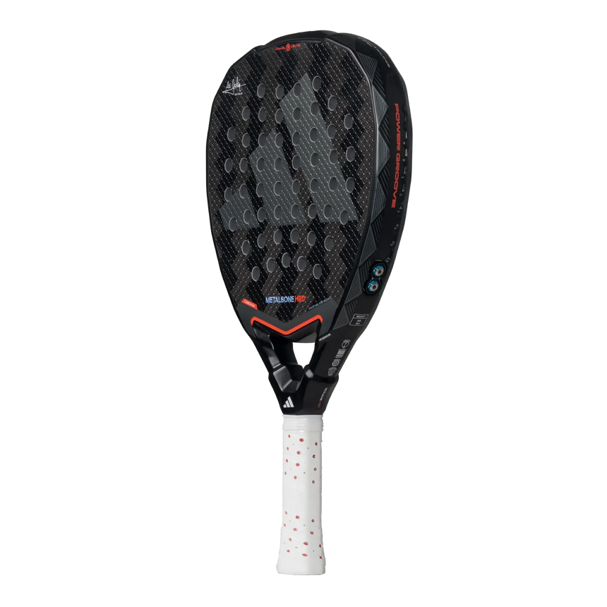 The Adidas Metalbone HRD+ 3.4 Ale Galan 2025 padel racket, designed for offensive play, has a black and gray honeycomb-patterned face with red accents, a white grip, and small blue decorative elements on the frame. The brand logo is prominent for easy customization.