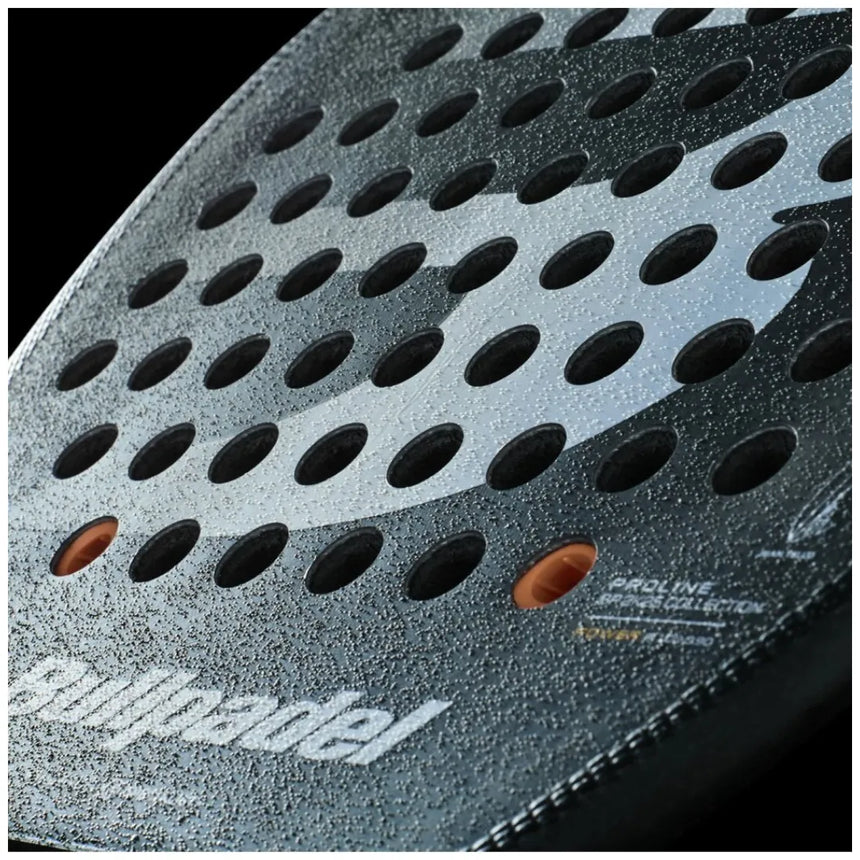 Close-up of a black padel racket with circular holes and glossy finish. The Padel Smash Academy brand is visible, highlighting its VERTEX 04 2025 JUAN TELLO model from the Proline Collection, offering total control with a textured dotted pattern for enhanced play.