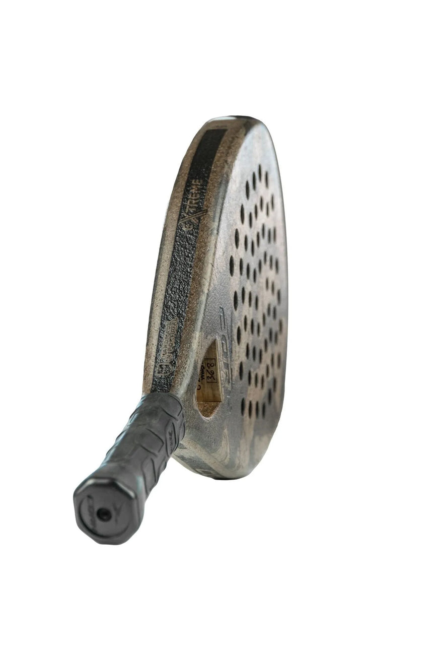 Close-up of the Cork Padel Extreme Black paddle, highlighting its high-performance design with a perforated oval head and textured grip handle, set against a plain white background.