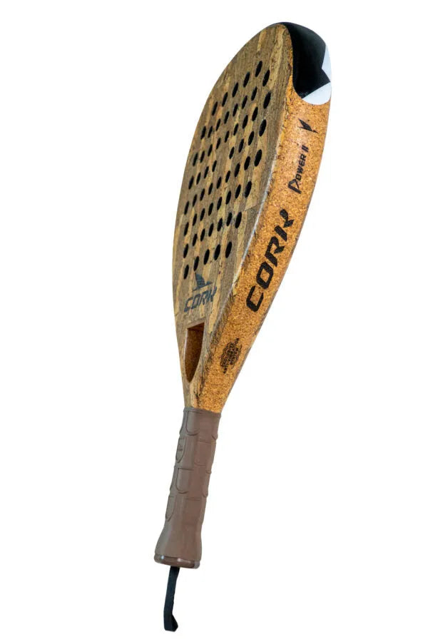 The Cork Padel Premium Power II Racket, by Cork Padel, is for advanced to professional players. Its designed with a cork body, brown handle and strap, teardrop shape, Cork Prowess 1 text, circular holes, and a black section with a white arrow for offensive appeal.