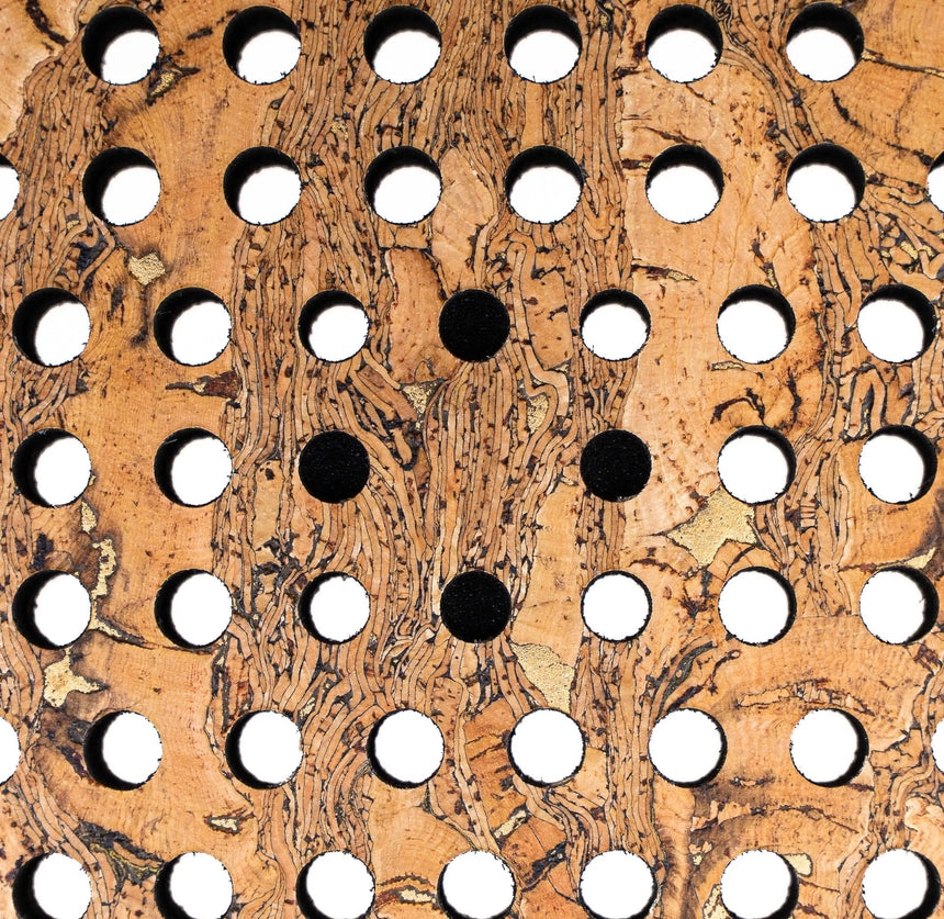 The Cork Padel Supreme Control III by Cork Padel features a cork surface with a geometric pattern of circular holes, highlighting control and precision. Five black circles form an X at the center, ideal for advanced defensive play, surrounded by white circles on a wood grain pattern.