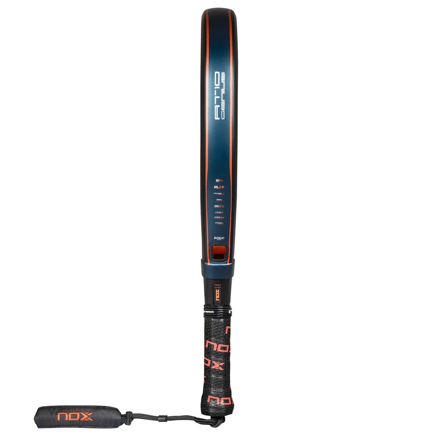 The Nox Padel Racket AT10 Genius Attack 18K Alum 2025 by Agustin Tapia features a diamond design with a dark blue frame, orange trim, and an 18K carbon surface. It has a black grip with lanyard and Enhanced Spin Technology for top performance. The NOX brand name appears on the grip and frame.