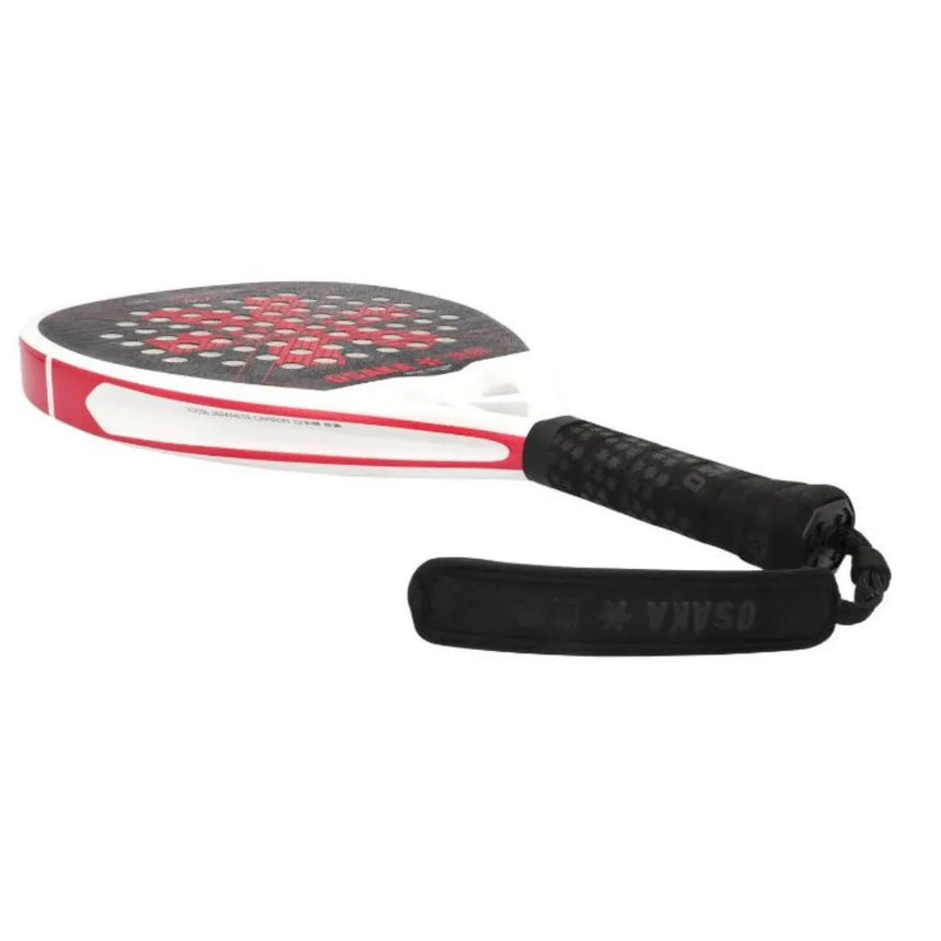 The Osaka Padel Racket Pro Tour Power 2024 (Like New) features a white frame, black grip, red accents, and Osaka branded strap. Its face is designed with a striking black and red pattern with circular holes made from durable 18K Textreme® Carbon for top performance.