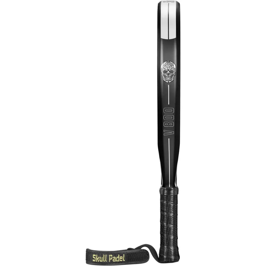 A SKULL PADEL V800 - 1K WHITE racket stands vertically on a white background, highlighting its skull design and textured handle with a black strap. It features an EVA rubber core and carbon surface, with Skull Padel and V800 prominently displayed.