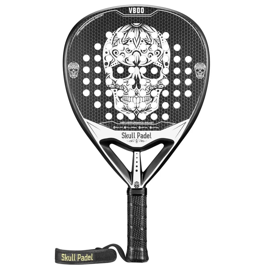 The SKULL PADEL V800 - 1K WHITE (LIKE NEW) by Skull Padel features a black and white design with a decorative skull on the carbon surface, a perforated face, EVA rubber core, black grip, and Skull Padel wrist strap.