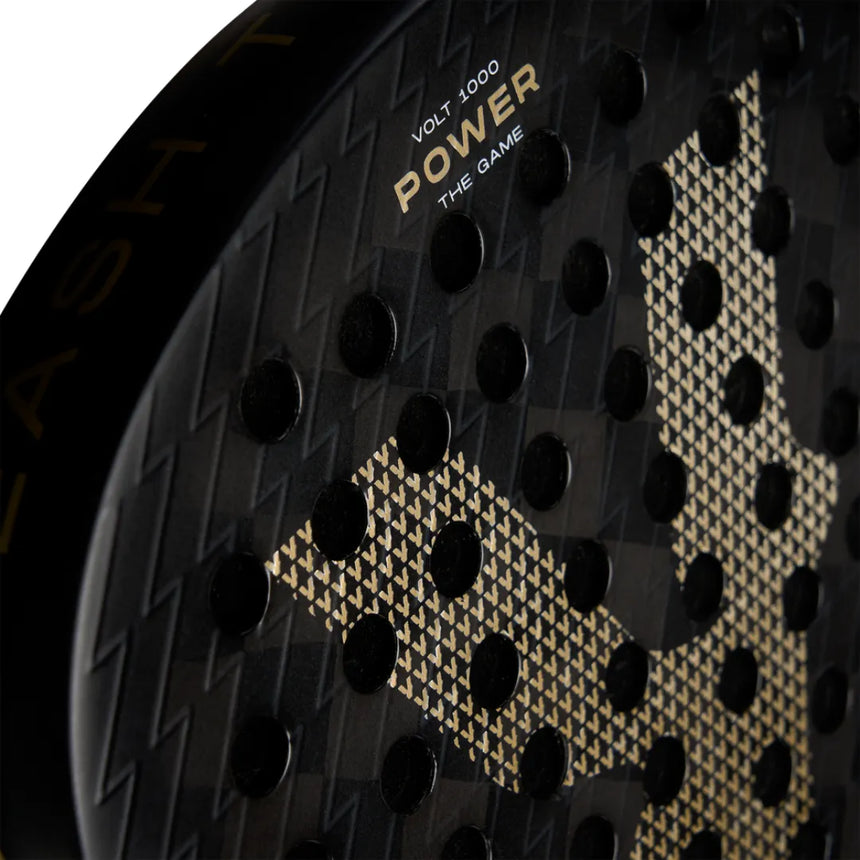 Close-up of the VOLT 1000 v4 Padel Racket by Volt, showcasing a black design with a textured surface and striking gold geometric pattern. The carbon structure boosts performance with circular perforations, and text reads VOLT 1000 Power The Game.