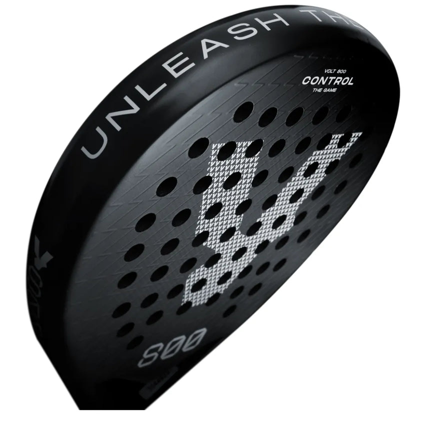 Close-up of a black VOLT 800 V4 padel racket by Volt featuring a perforated surface. The edge displays Unleash the, model details, and Control. It has advanced shock absorption, a 3K carbon structure, and a central stylized white V.