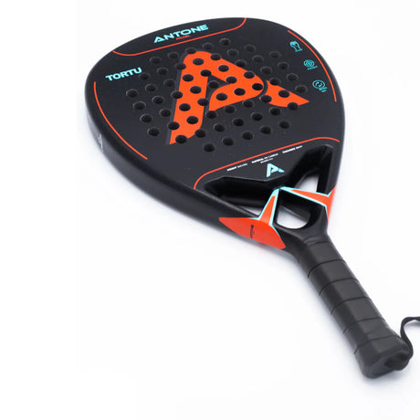 Close-up of the high-performance Antone Padel Tortu racket, showcasing its black and red design with 12K carbon construction. It features a hole pattern, a large red A, and black tape on the grip.