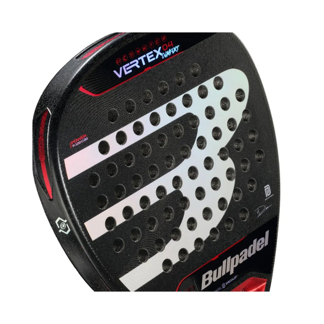 Close-up of the Bullpadel Vertex 04 Comfort 2024 Martín Di Nenno padel racket, featuring a black design with a large B logo. This diamond-shaped racket has a Top Spin surface, circular holes, and red and silver accents, with the brand name on the lower right.