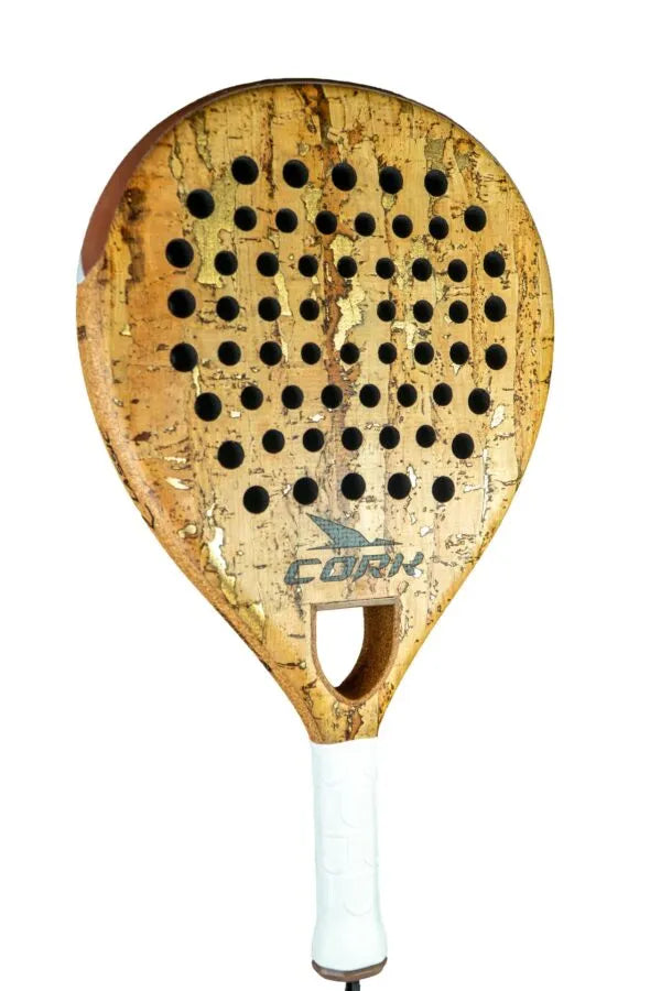 A close-up of the Cork Padel Classic Racket shows its light brown, textured surface with a unique drilling pattern of circular holes. The racket features a white grip handle for comfort and control, with Cork Padel elegantly printed on it.