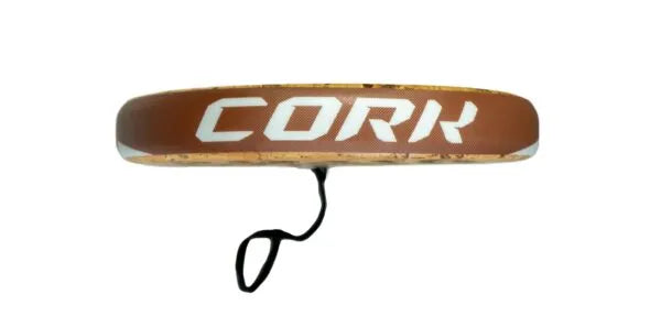The brown Cork Padel Classic frisbee, featuring CORK in white letters, mirrors the design of the Cork Padel Classic Racket. Equipped with a black comfort strap for enhanced control, it showcases an innovative drilling pattern against a plain white backdrop.