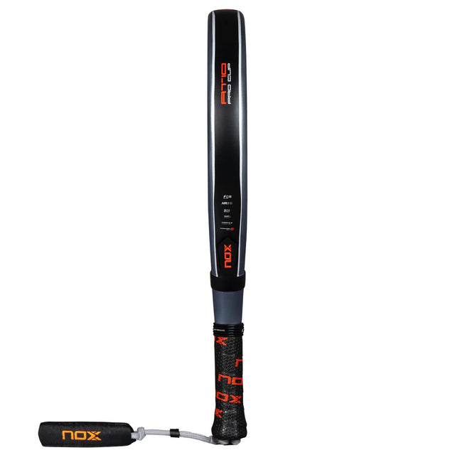 The Nox Padel Racket AT Pro Cup Comfort 25 by Agustín Tapia features a black and red design with photochromic paint and a textured grip, complete with a wrist strap. It includes Fiber Glass Silver technology for enhanced performance.