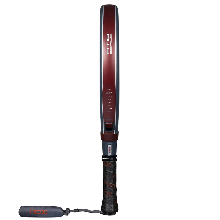 The NOX Padel Racket AT10 Genius 12K by Agustin Tapia 2025, with a red frame and black grip, is shown vertically on a white background. It features Exclusive Spin Technology and has Nox visible on the frame and cord, indicating precision and power in every swing.