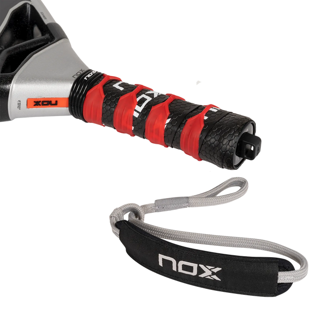 Close-up of the NOX Padel Racket AT10 Genius 18K handle, wrapped in black and red grip tape. Enhanced with EOS Flap technology, it includes a gray wrist strap showing the NOX brand and features a textured, contrasting color design.