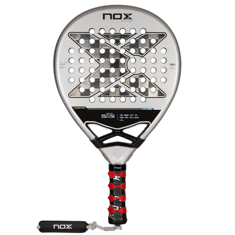 The NOX Padel Racket AT10 Genius 18K by Agustin Tapia from Padel Smash Academy features a silver face with black X-design holes, a black handle with red grip accents, and EOS Flap technology. Its champion Agustín Tapias choice.