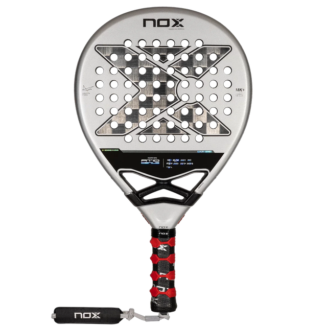 The NOX Padel Racket AT10 Genius 18K by Agustin Tapia from Padel Smash Academy features a silver face with black X-design holes, a black handle with red grip accents, and EOS Flap technology. Its champion Agustín Tapias choice.