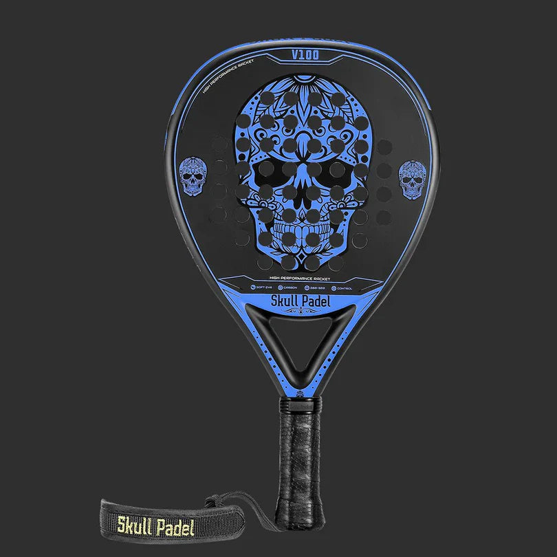 The SKULL PADEL V100 | BLUE EDITION (KIDS) from Skull Padel features a striking blue and black design with an ornate skull on the face. It includes a wrapped grip and a Skull Padel wrist strap against a dark background.