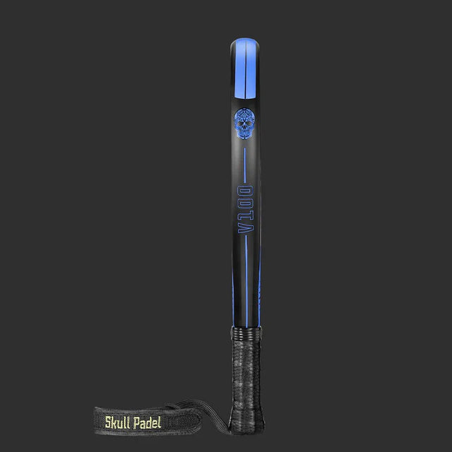 The SKULL PADEL V100 | BLUE EDITION (KIDS) features a black racket with blue accents, a skull logo, and VILLO vertically on the face. It has a black grip, and the strap displays Skull Padel in green on dark gray. Perfect for kids starting padel.