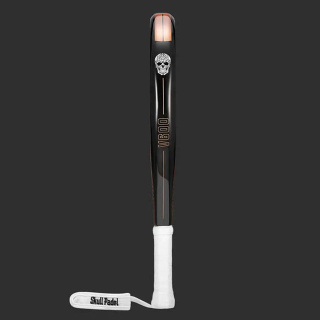 The SKULL PADEL V600 - 12K COPPER SKULL is a like-new padel racket for intermediate players. It has a black and orange design with a skull logo, V800 printed vertically, carbon fiber build, dark gray background, white grip tape handle, and a wrist strap labeled Skull Padel.