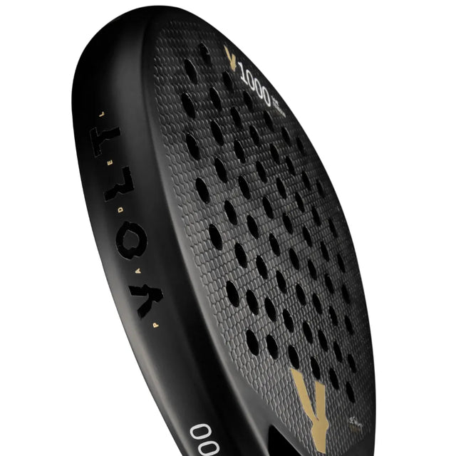 Close-up of a black VOLT 1000 V23 Padel Racket by Volt, showcasing a textured surface and circular holes with VOLO in gold. The diamond-shaped blade suggests an aggressive playing style against a white backdrop.