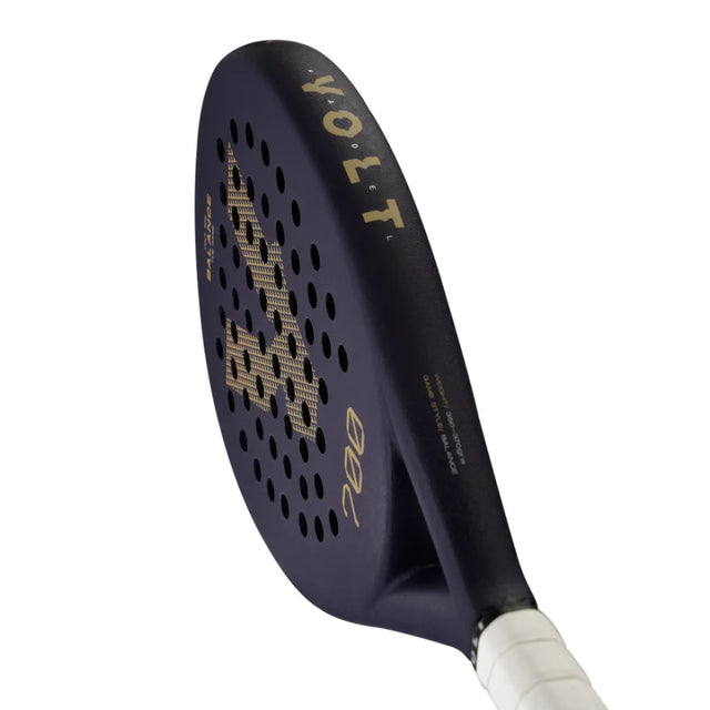 The VOLT 700 v4 padel racket by Volt boasts a black round head and white grip, gold accents, VOLT branding, and circular perforations. Its 3K carbon structure with flexible shock absorption technology enhances on-court performance.